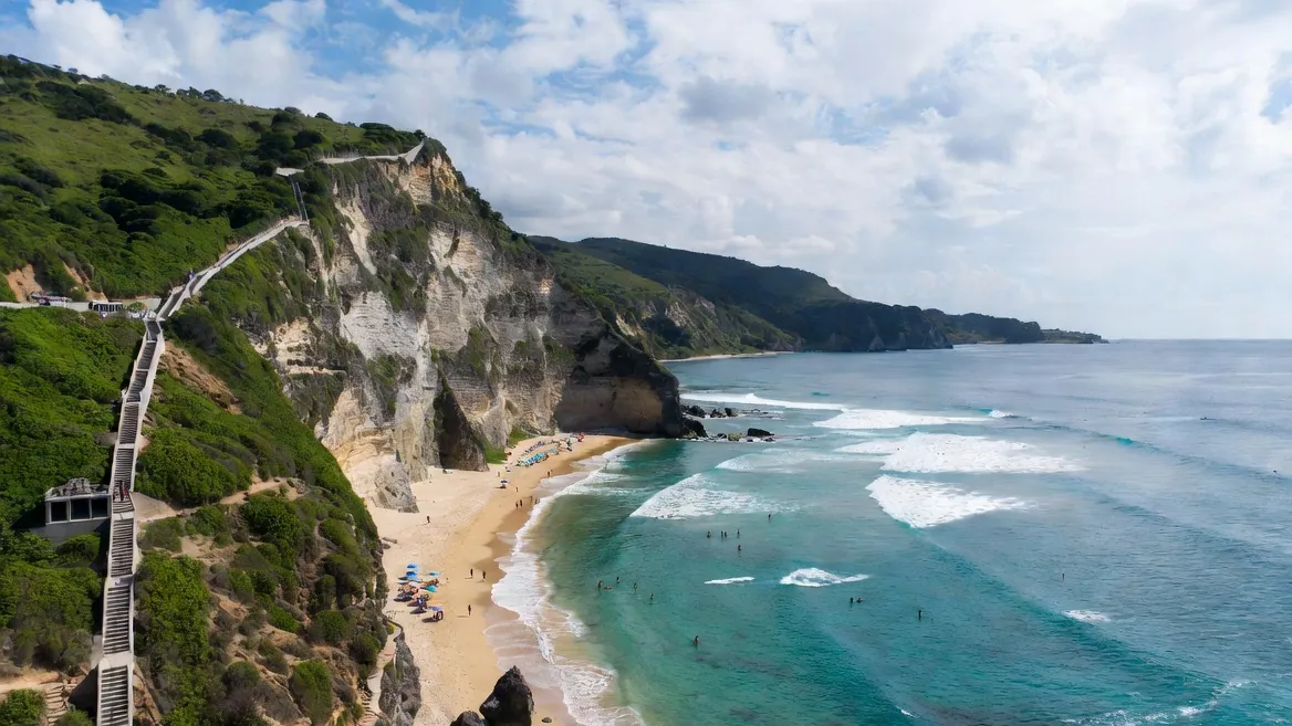 Carrizalillo cove from the clifftop stairs: calm turquoise water and palapas on a sheltered beach