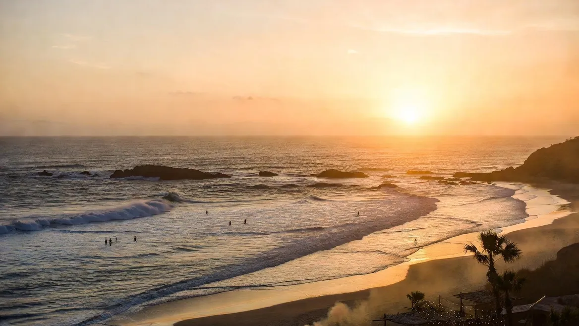 Sunset at La Punta: small left-hand waves peeling off the point with longboarders in the lineup