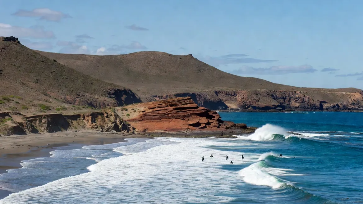 The red headland and wedging shorebreak of Punta Colorada, empty except for a few bodyboarders