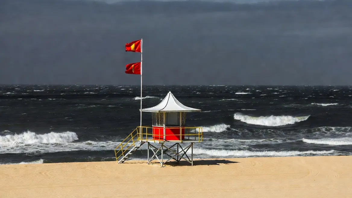 Warning flags flying at an empty lifeguard tower — the ocean is the real danger here